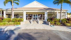 A hotel with a central entrance, palm trees, and a clear blue sky. - Pet-Friendly 2BR Condo–Cedars East #810 by RVA (Longboat Key)