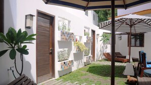 Un patio con un banco de madera, una piscina pequeña y un muro de azulejos con jardineras.