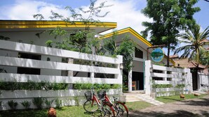 Un edificio con fachada blanca, techo amarillo y un letrero que indica un negocio o servicio.