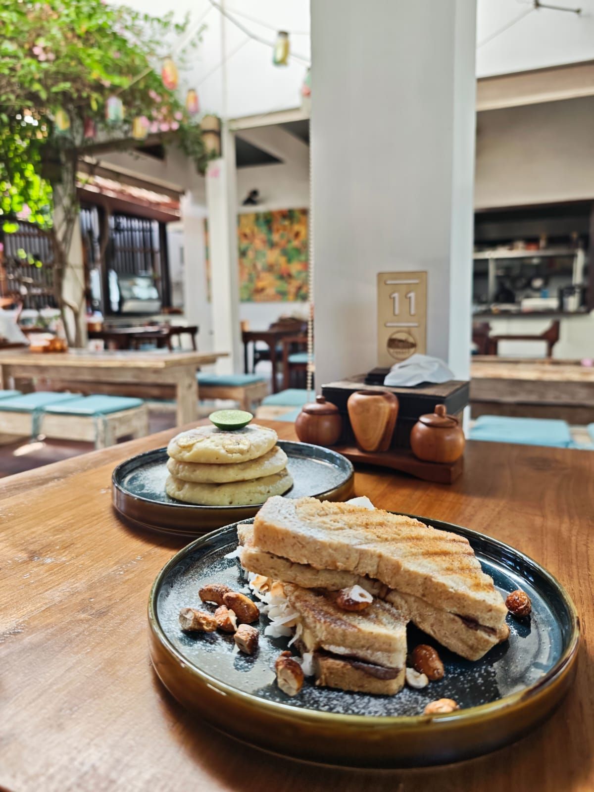 A table with a plate of food, a teapot, and a number 11 sign in a cafe setting.