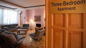 Un apartamento de tres habitaciones con una sala de estar que incluye un conjunto de sofás, sillones y una mesa de centro.