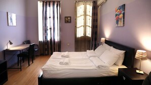 Una habitación de hotel con cama, escritorio, silla y lámpara.