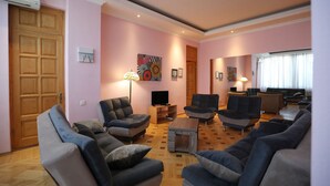 Una sala de estar con puerta de madera, televisor y varios sofás.