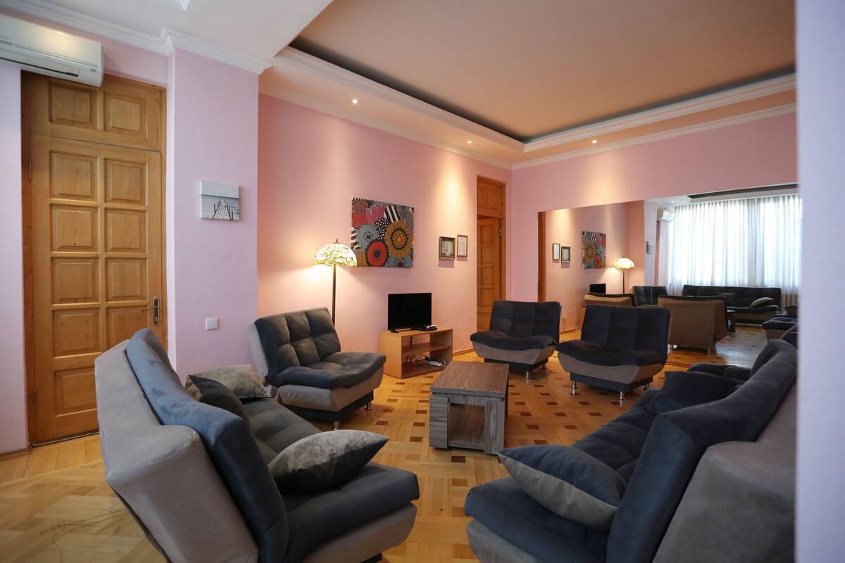 A living room with a wooden door, a television, and multiple sofas.