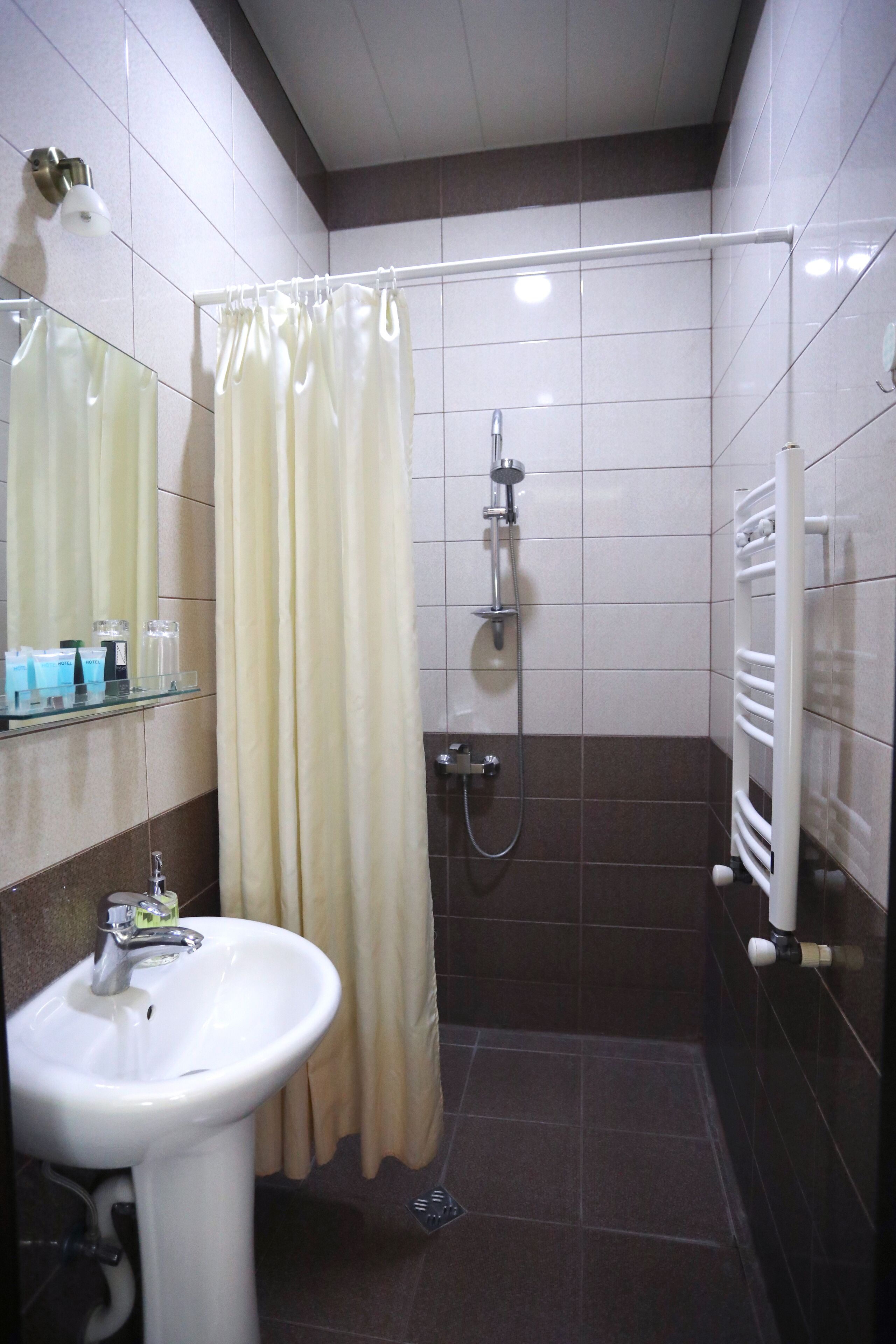 Une salle de bain équipée d’une douche, d’un lavabo, d’un miroir et d’un porte-serviettes.