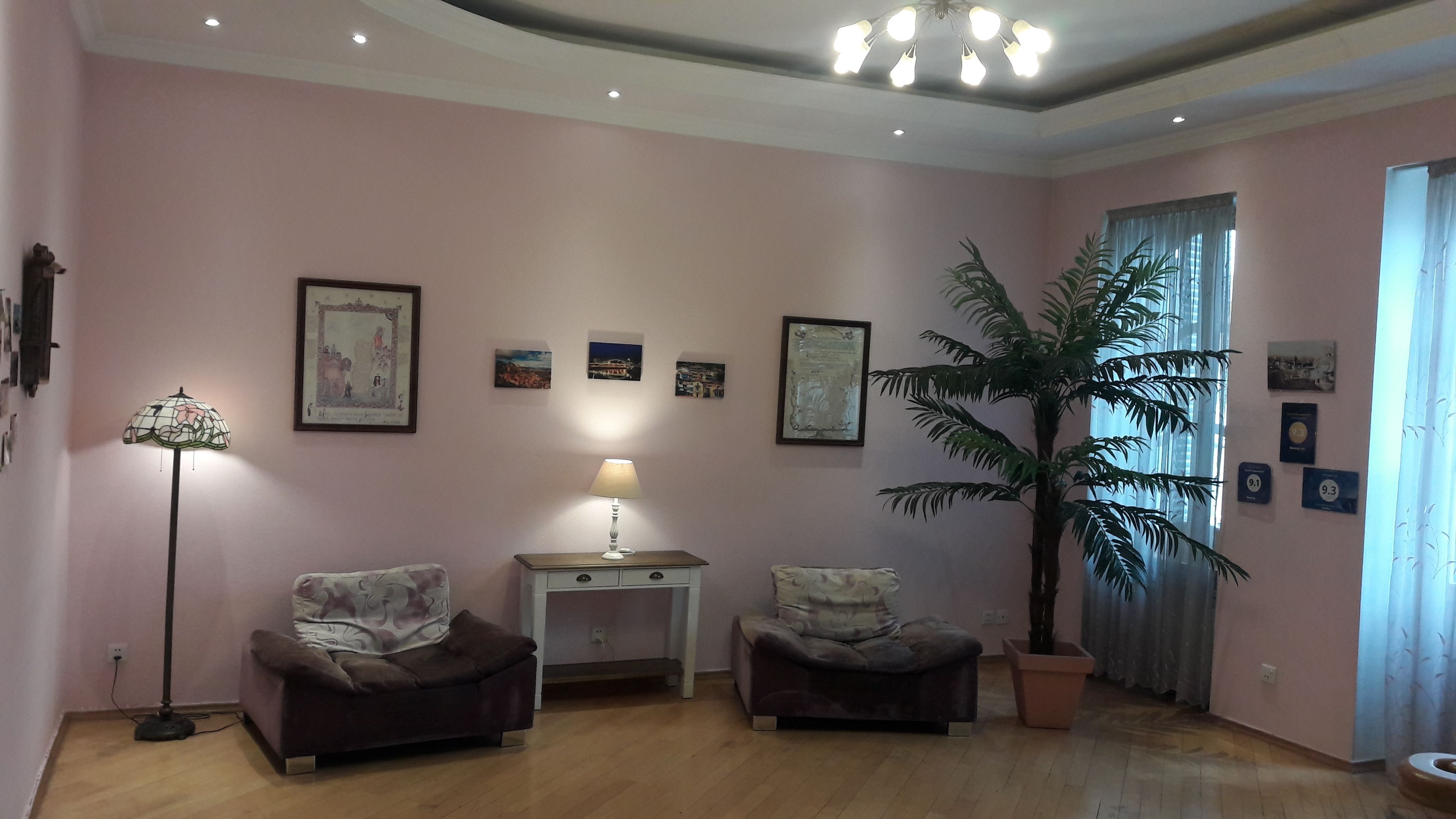 Sala de estar con dos sillones, una lámpara de pie, una mesa y una gran planta en maceta.