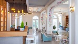 Ampla área de estar com mobiliário branco, balcão de recepção de madeira e luminárias decorativas.
