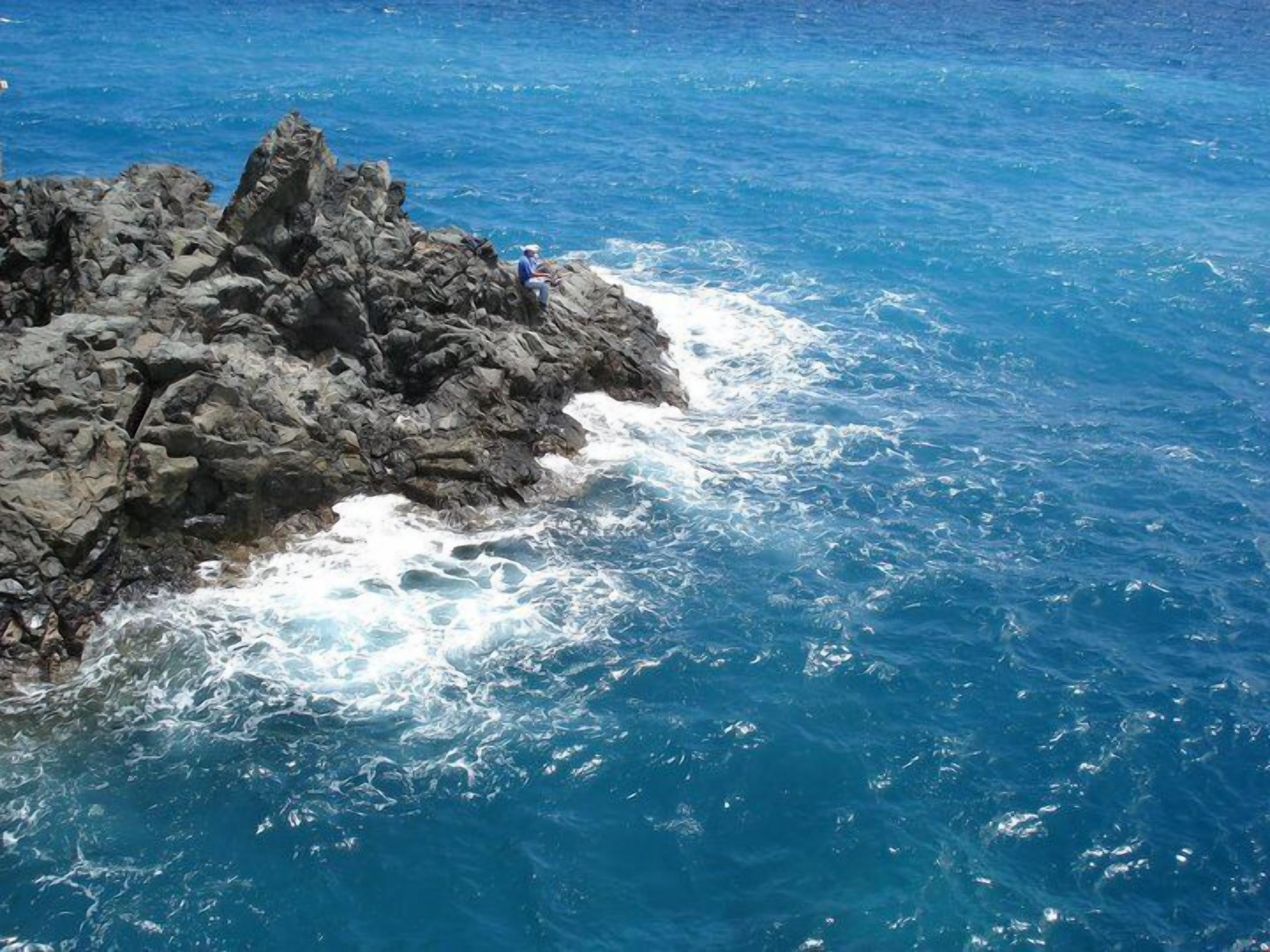 Une côte rocheuse bordée d’une eau d’un bleu limpide.