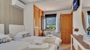 Habitación de hotel con dos camas, un armario de madera, televisor y vista a las montañas.