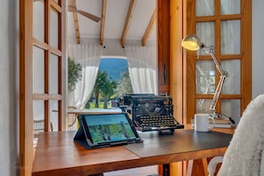 Un bureau en bois avec un ordinateur portable, une machine à écrire, une lampe et une tasse.