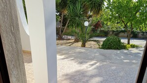 Una entrada limpia con felpudo, un camino de baldosas y vistas al exterior con árboles y una pared.