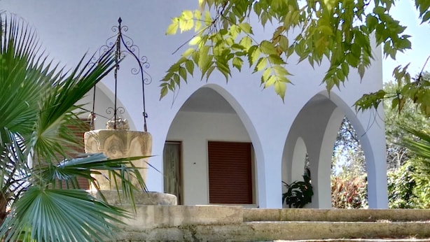 Un edificio con arcos blancos y una fuente de piedra.