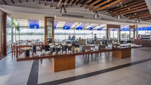 A modern cafe with a long wooden counter, tables, and chairs.