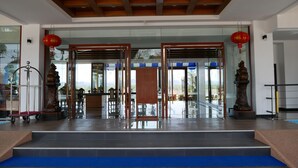 A hotel lobby with a reception desk, seating area, and a staircase leading to the upper floor.