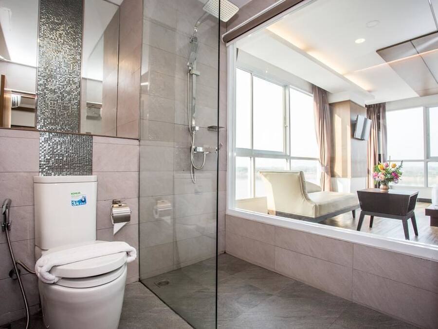 Un baño moderno con cabina de ducha de vidrio, inodoro y un amplio ventanal con vista a la ciudad.