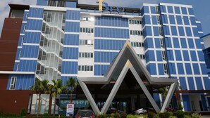 A modern hotel building with a prominent 'Blu Hotel' sign, multiple floors, and a unique geometric entrance structure.