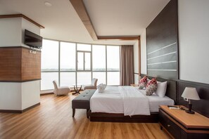 Habitación de hotel moderna con una cama grande, televisión, escritorio y vistas a la ciudad.
