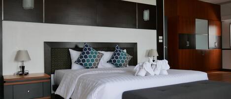 A modern hotel room with a large bed, a bedside table, a bench, and a wardrobe.