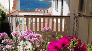 A balcony with a view of the sea, a white building, and pink flowers in the foreground. - PINK BAY HOUSE 100 MT FROM THE SEA  (Marina San Gregorio)