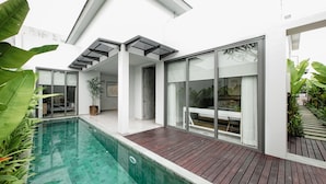 Una casa moderna con piscina, puertas de cristal amplias y una terraza de madera.