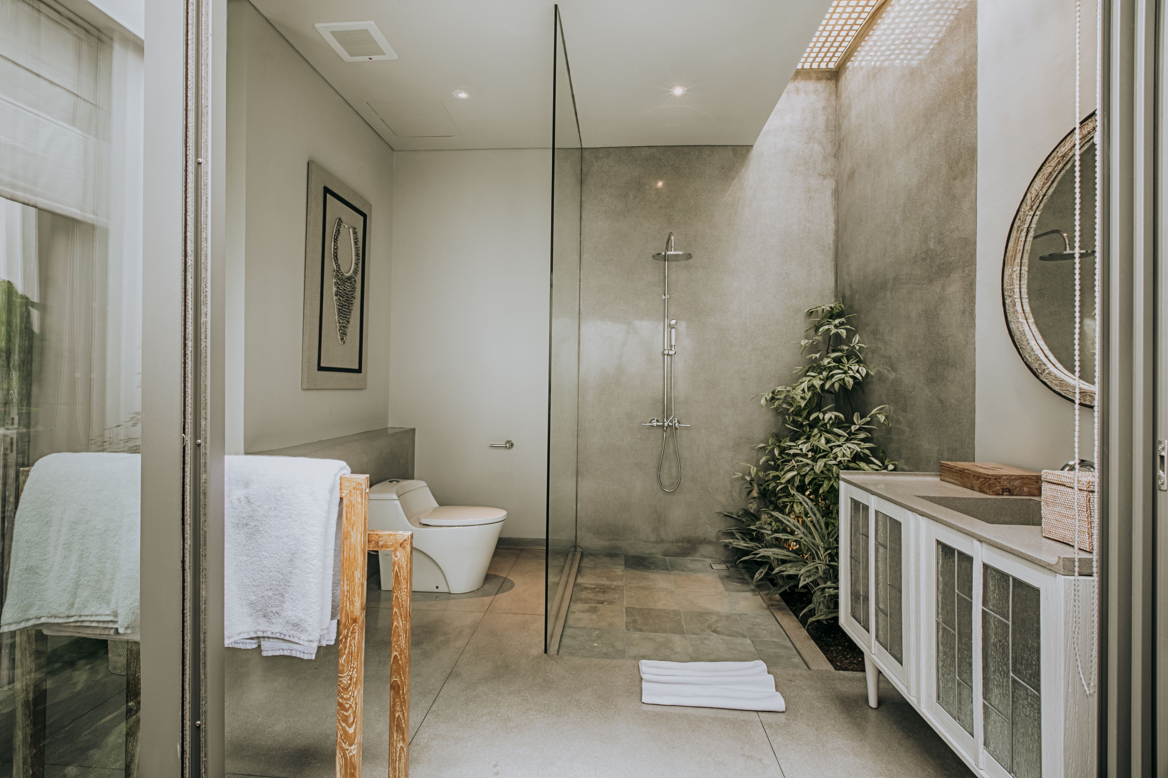 A modern bathroom with a glass-enclosed shower, a toilet, a sink with a cabinet, and a mirror.