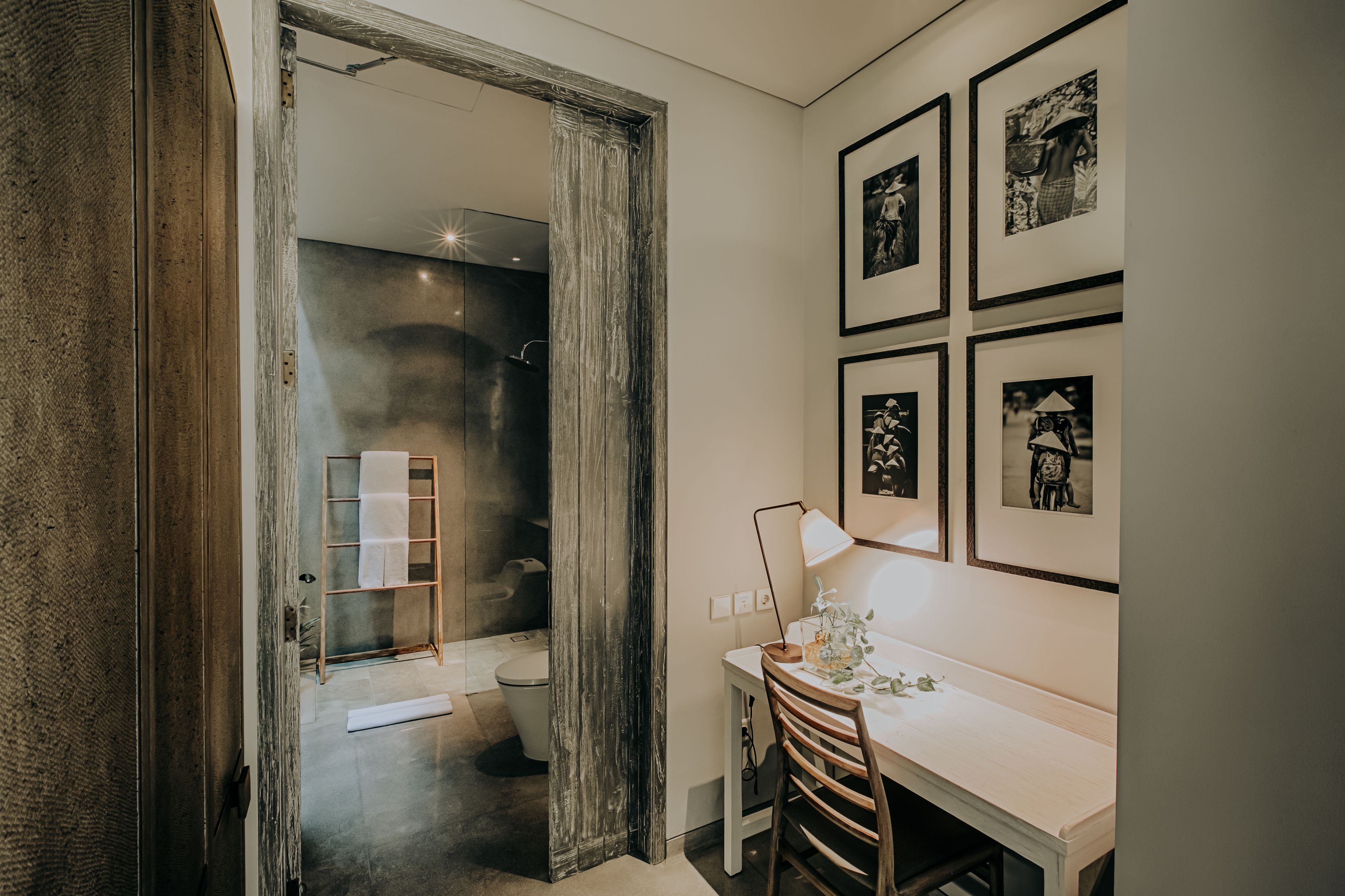 Een moderne badkamer met een douchecabine van glas, een houten deur en een witte wastafel met spiegel.