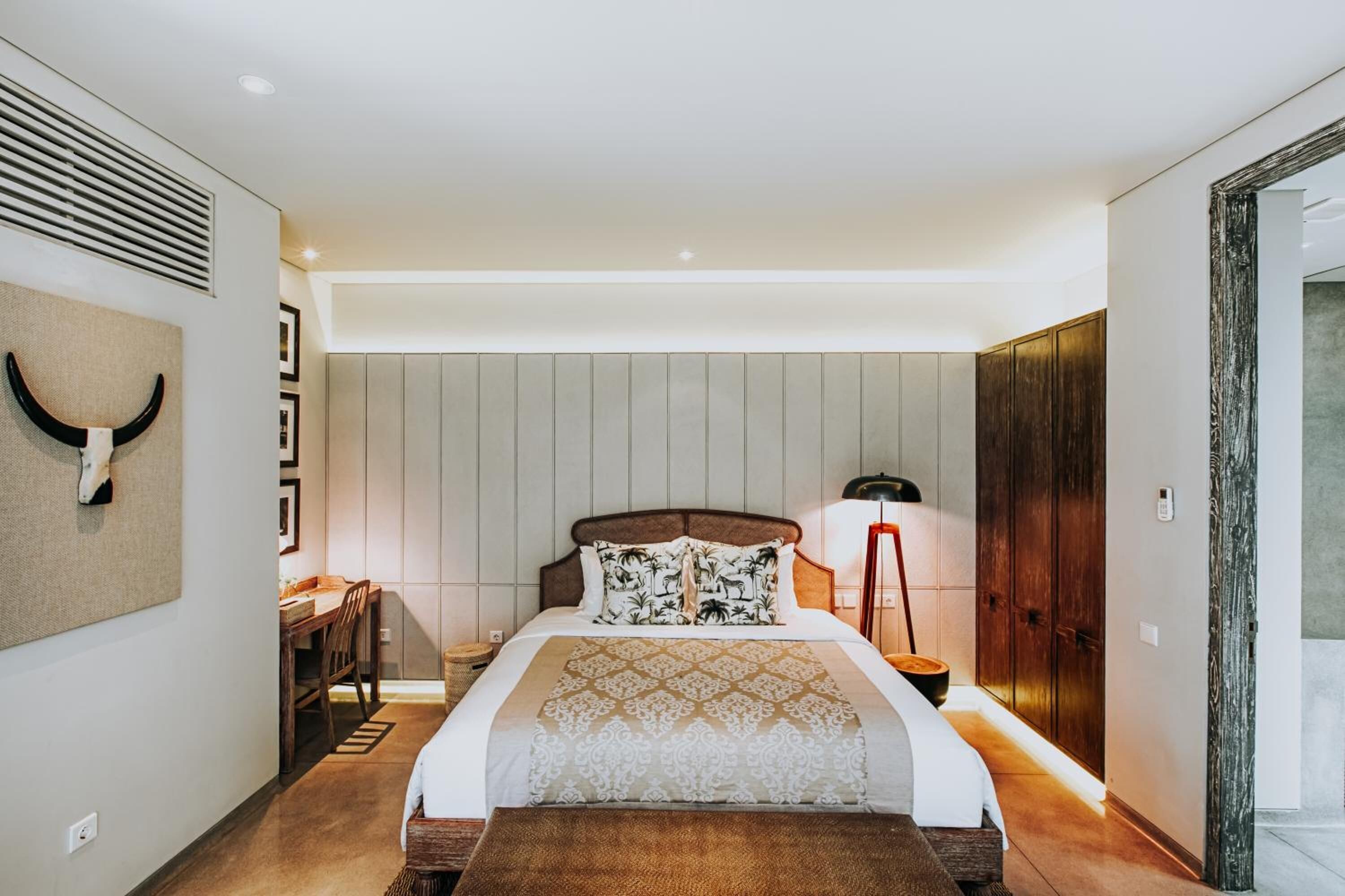 A modern bedroom with a large bed, a desk, and a chair.