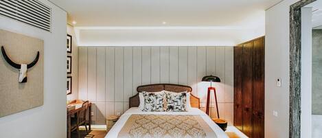 A modern bedroom with a large bed, a desk, and a chair.