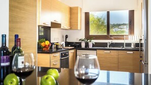 A modern kitchen with wooden cabinets, a black countertop, and a window with a view of greenery. - Four Bedroom Front Line (Sea-Front) villa located in an excellent location in the area of Cape Greco (Protaras)