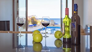 A table with two wine glasses, three green apples, and two bottles of wine. - Four Bedroom Front Line (Sea-Front) villa located in an excellent location in the area of Cape Greco (Protaras)