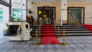 En hotellentrén med en röd matta, en receptionsdisk och en trappa som leder upp till lobbyn.