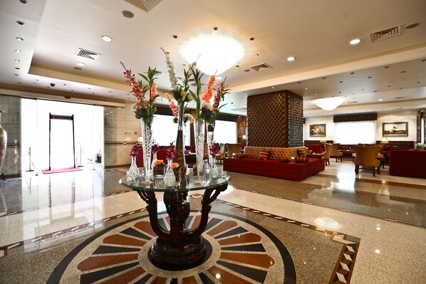 A lobby with a glass-top table, red sofas, and a patterned floor.