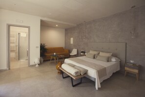 A modern bedroom with a large bed, bedside tables, a sofa, and a small table with a plant. - AVANTGARDE Hotel Residence (Conversano)