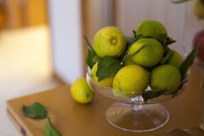 A clear glass bowl containing lemons with green leaves, placed on a wooden surface. - AVANTGARDE Hotel Residence (Conversano)
