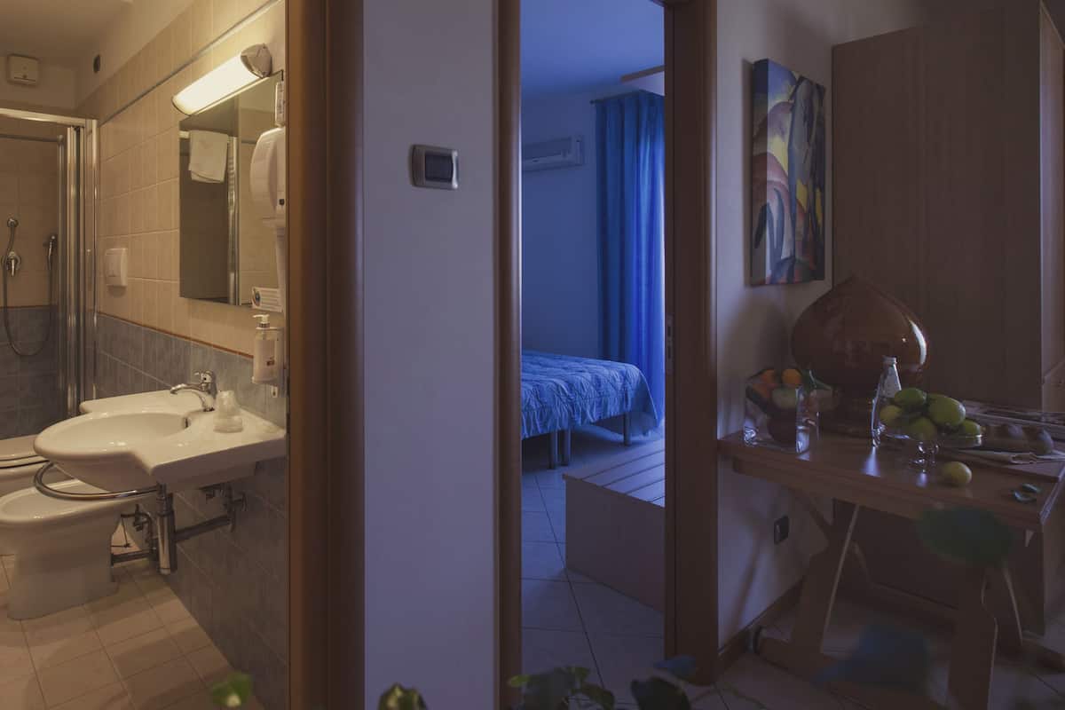 A hotel bathroom with a sink, mirror, and shower.
