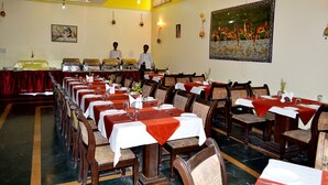 Un restaurante con mesas largas, sillas y una zona de bufé.
