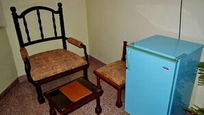 Una habitación con una silla de madera y un refrigerador pequeño azul.