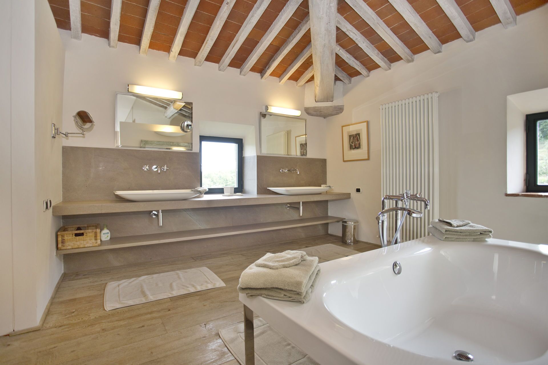 A modern bathroom with a large bathtub, two sinks, and a wooden ceiling.