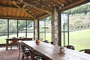 A covered outdoor dining area with a long wooden table, several chairs, and a stone pillar. - Beautiful  villa for 16 people with private pool, WIFI, A/C, TV, patio and panoramic view (San Vincenti)