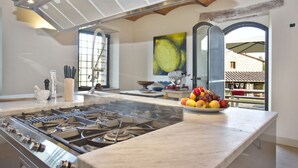 Une cuisine moderne équipée d’une cuisinière à gaz, d’un plan de travail en marbre et d’un saladier rempli de fruits.