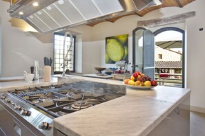 A modern kitchen with a gas stove, a marble countertop, and a bowl of fruit. - Beautiful  villa for 16 people with private pool, WIFI, A/C, TV, patio and panoramic view (San Vincenti)