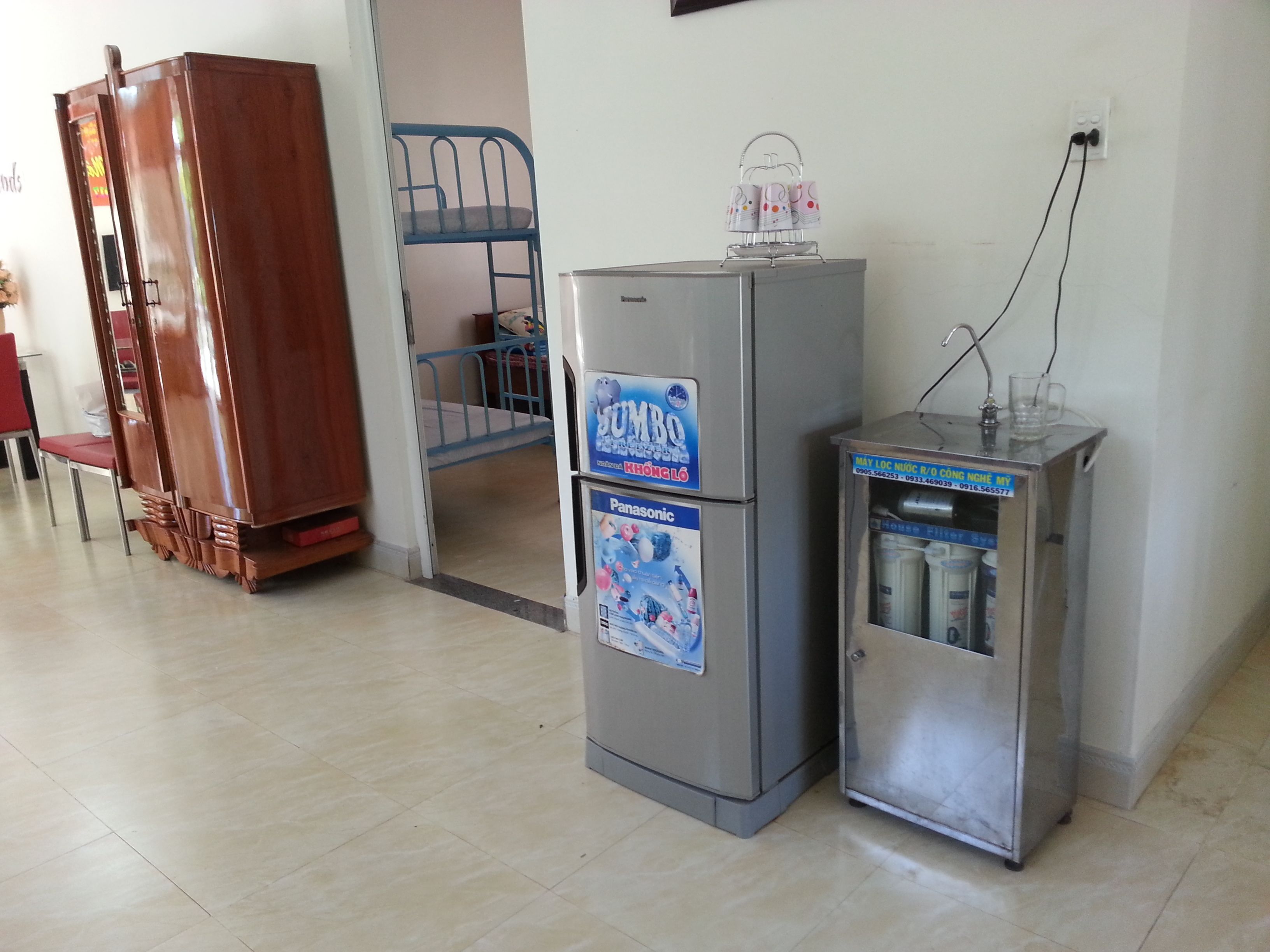 A compact kitchenette with a refrigerator, a small freezer, and a water dispenser.