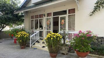 A two-story house with a balcony, potted plants, and a staircase leading to the entrance.