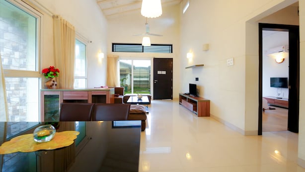 Amplia sala de estar con mesa de comedor, sillas, sofá, televisor y ventilador de techo.