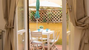 An outdoor patio with a table and chairs, a potted plant, and a wooden lattice fence.