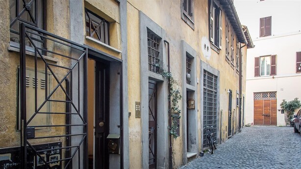 A narrow cobblestone street flanked by historic buildings with traditional shutters and metal gates.