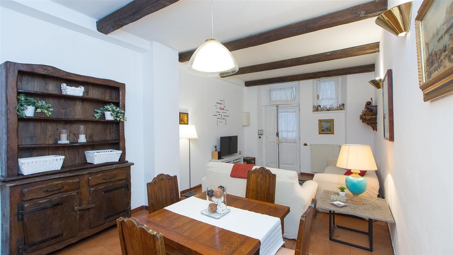 Zona de dinar amb taula de fusta, cadires i un armari per a menjar.