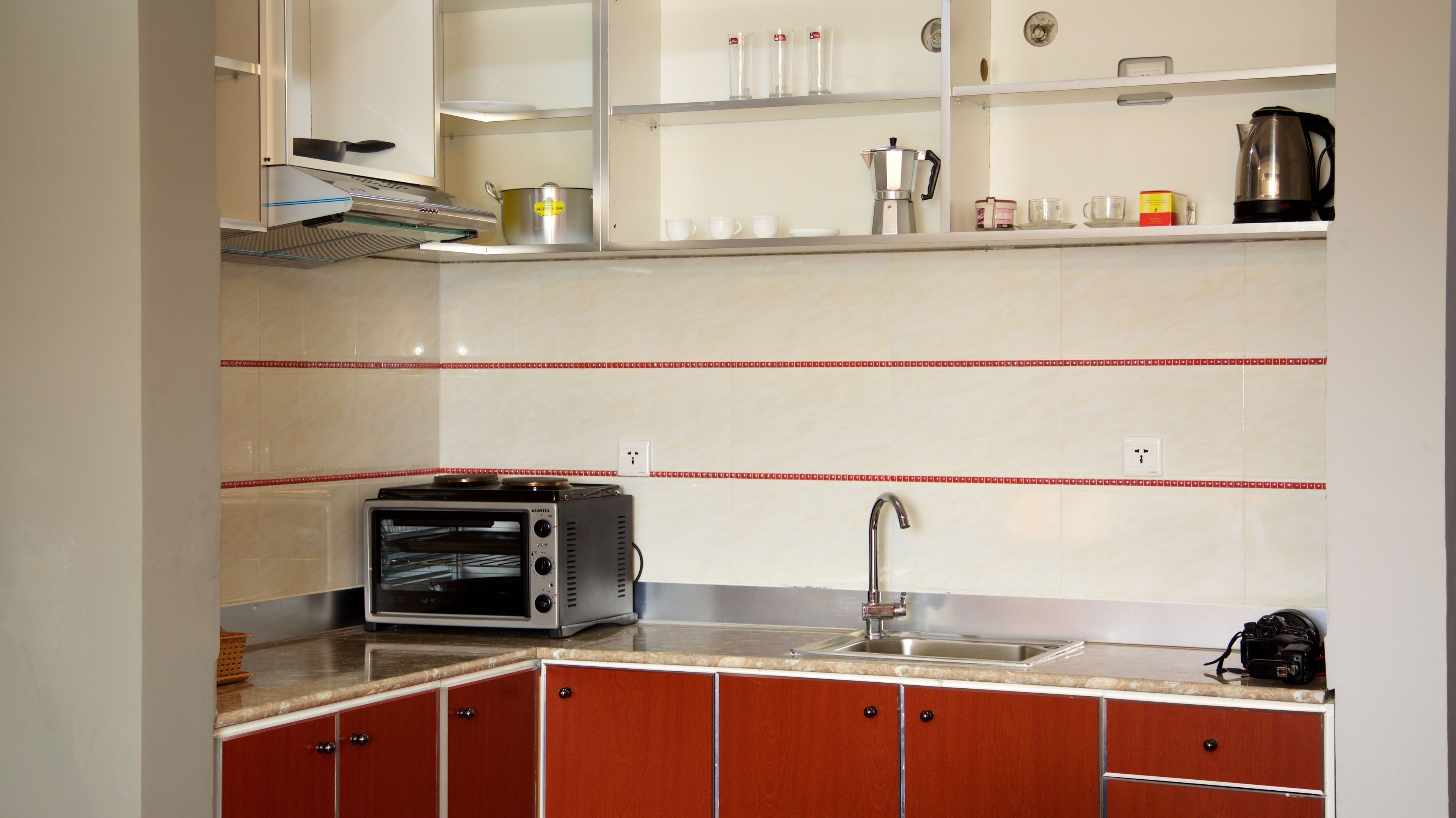 A kitchen with a built-in oven, a sink, and a coffee maker on the countertop.