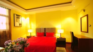A hotel room with a large bed, two bedside tables with lamps, a desk, and a chair. - YINM Luxury Apartment (Addis Ababa)