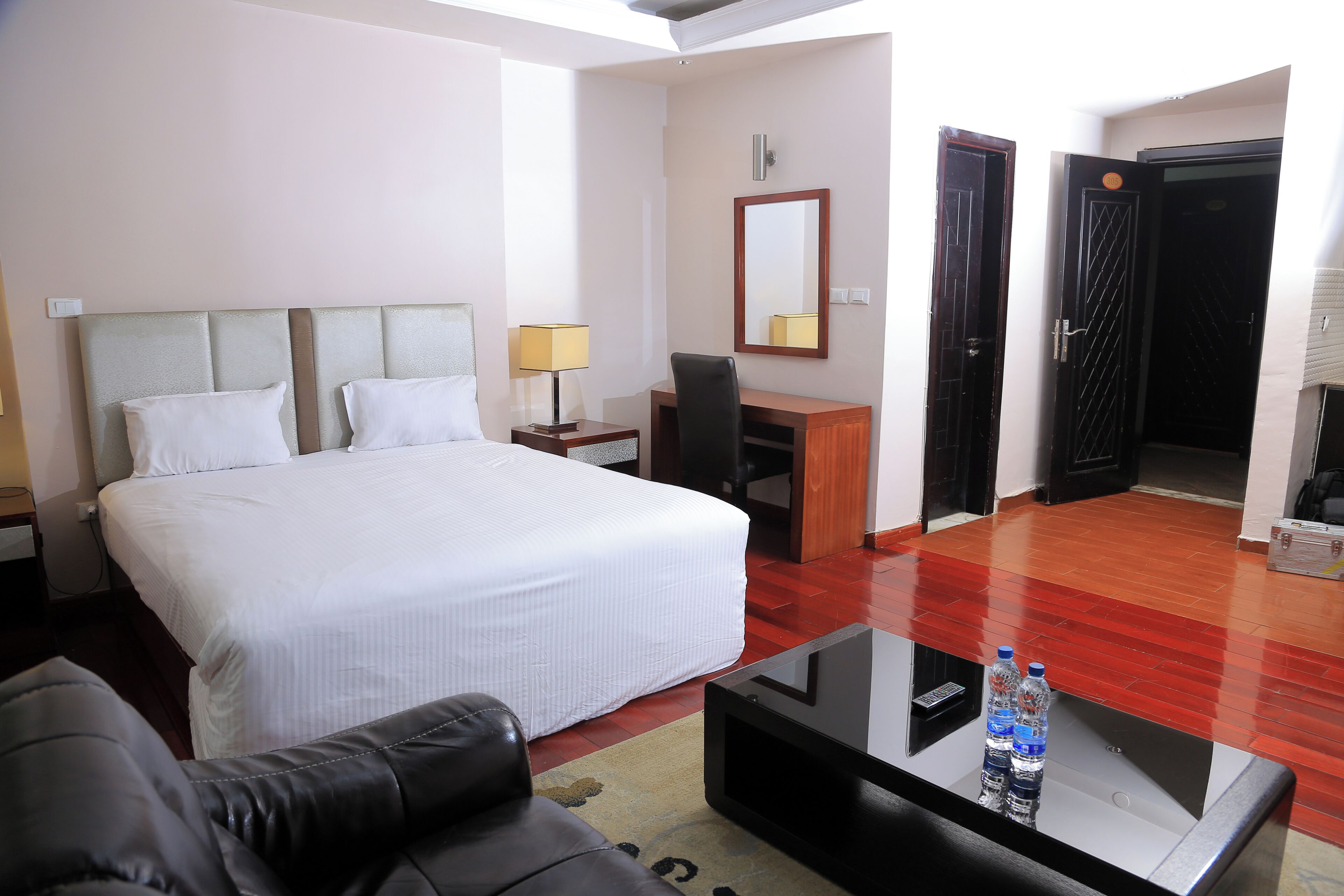 Habitación de hotel con cama, escritorio, silla, mesa de centro y espejo.
